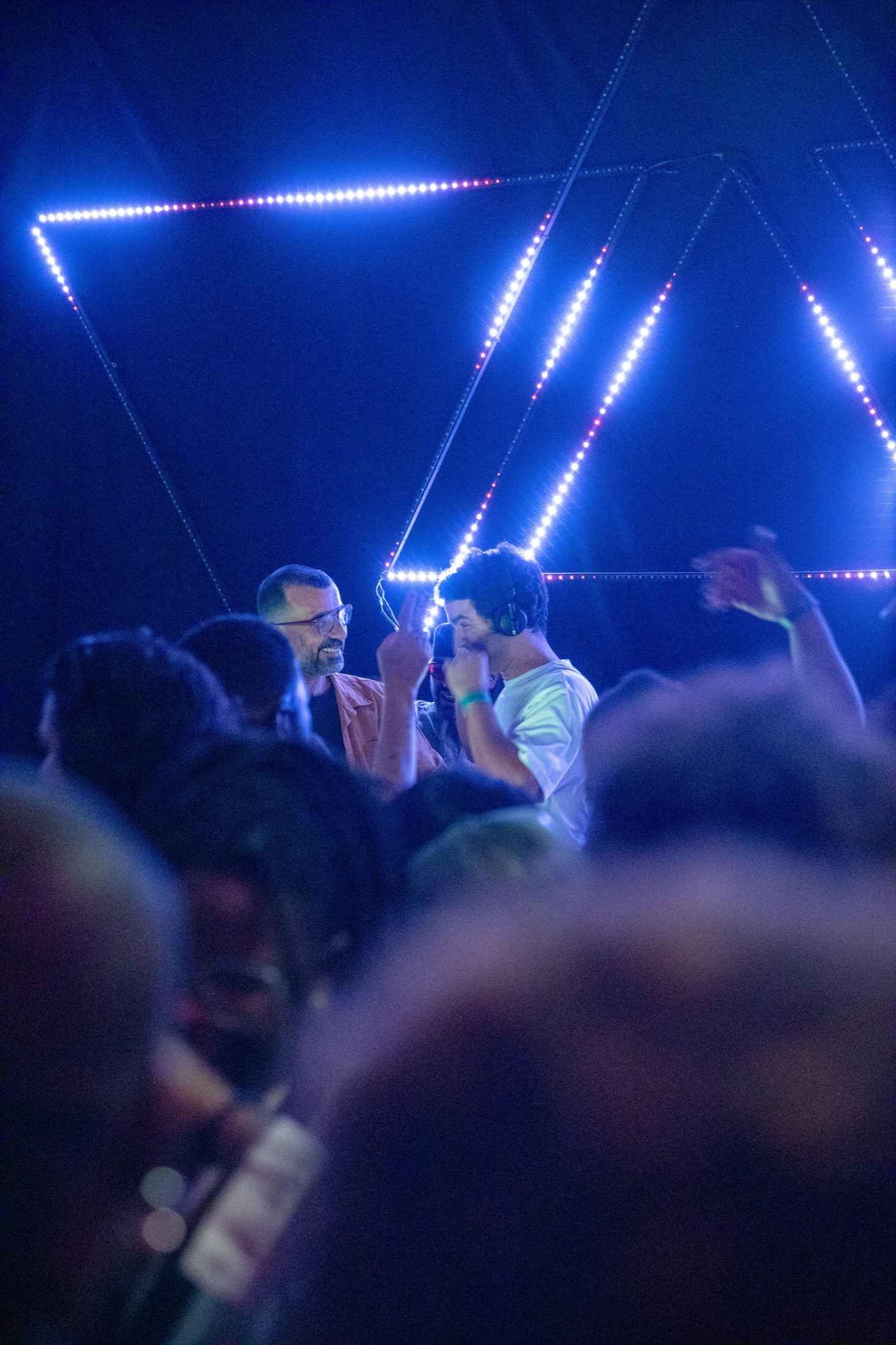 KULAS framed through a crowd under geometric blue lights.